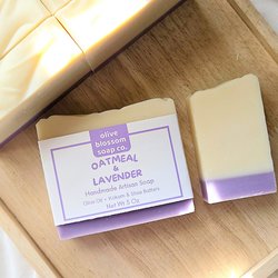 A white and purple bar of Handmade oatmeal and lavender soap on a wooden tray.